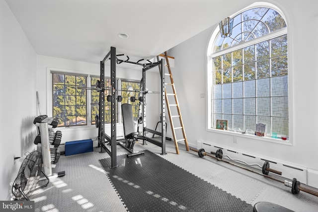 exercise room featuring a baseboard heating unit and carpet flooring