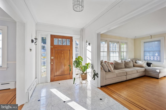 foyer entrance with ornamental molding, a baseboard heating unit, and light wood-type flooring