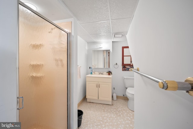 bathroom with a shower with door, a paneled ceiling, toilet, vanity, and tile patterned flooring