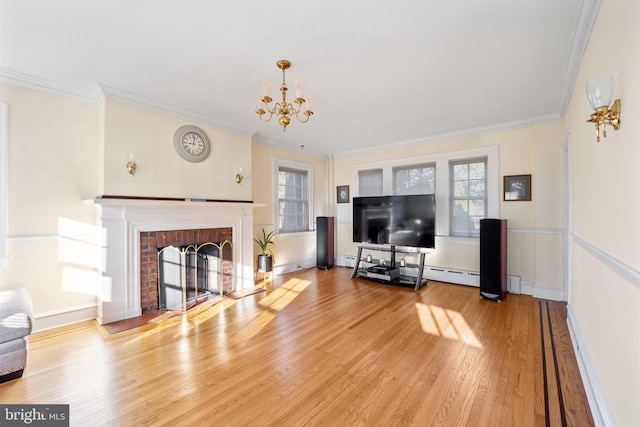 living room featuring light wood-type flooring, a brick fireplace, baseboard heating, crown molding, and a chandelier