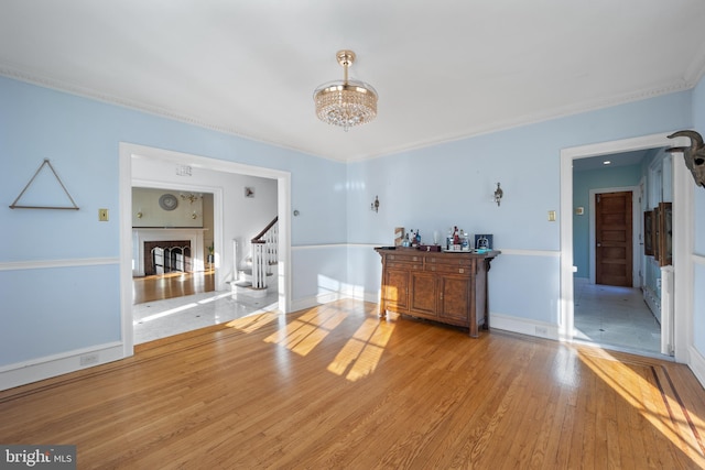 unfurnished living room featuring ornamental molding, light hardwood / wood-style flooring, and a chandelier