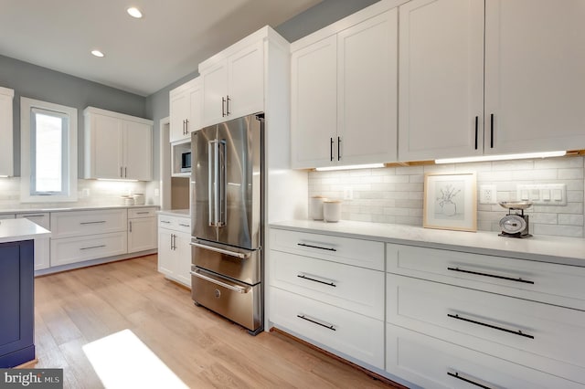 kitchen featuring tasteful backsplash, white cabinetry, high end fridge, and light hardwood / wood-style flooring