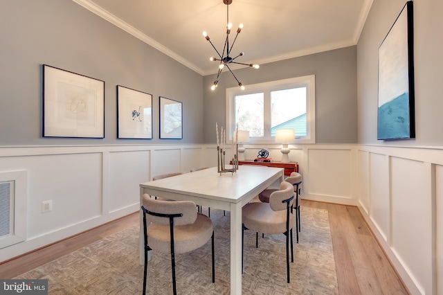 dining area featuring ornamental molding, light wood-type flooring, and an inviting chandelier