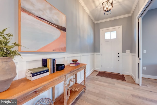 foyer entrance with a notable chandelier, light hardwood / wood-style flooring, and ornamental molding