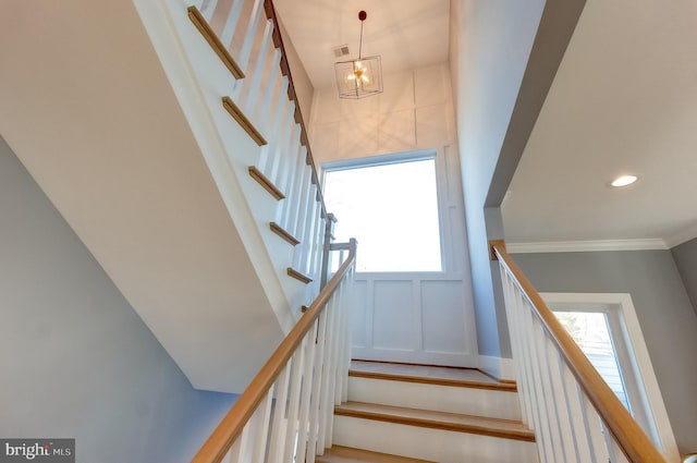 staircase featuring ornamental molding and a notable chandelier