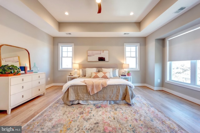 bedroom featuring a tray ceiling and light wood-type flooring