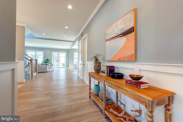 corridor with ornamental molding and light hardwood / wood-style floors