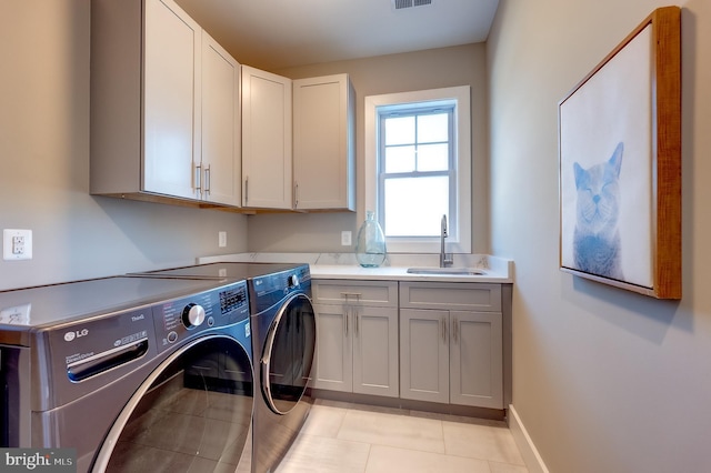 clothes washing area featuring cabinets, sink, washer and dryer, and light tile patterned flooring