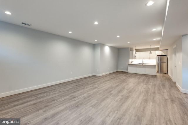 unfurnished living room featuring sink and light hardwood / wood-style flooring