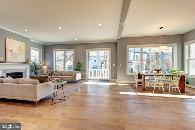 living room with beam ceiling, ornamental molding, and light wood-type flooring