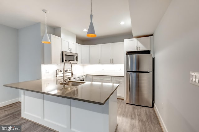 kitchen with white cabinetry, stainless steel appliances, kitchen peninsula, and pendant lighting