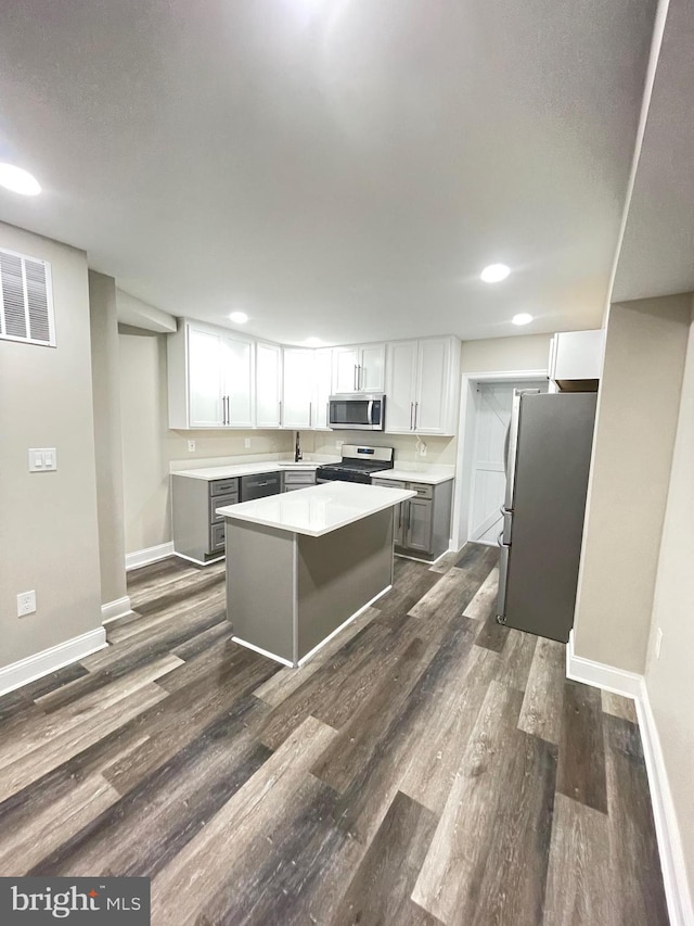 kitchen with white cabinetry, stainless steel appliances, dark hardwood / wood-style floors, and a kitchen island