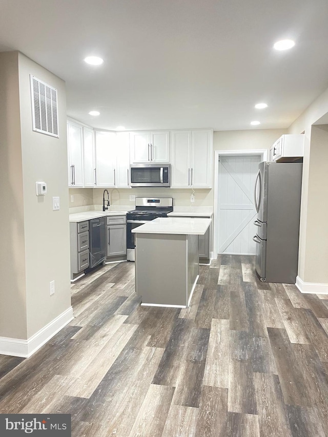 kitchen with gray cabinets, a kitchen island, white cabinetry, and appliances with stainless steel finishes