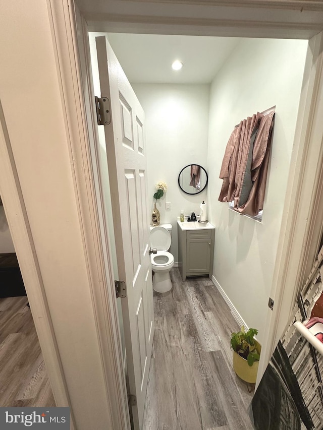 bathroom with toilet, hardwood / wood-style flooring, and vanity