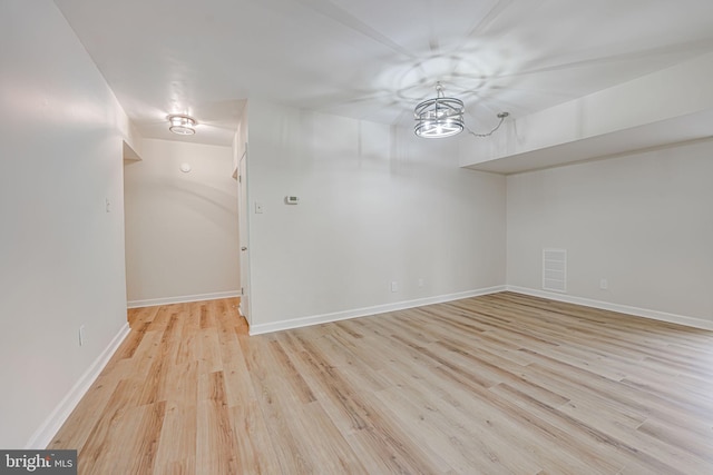 empty room with an inviting chandelier and light wood-type flooring