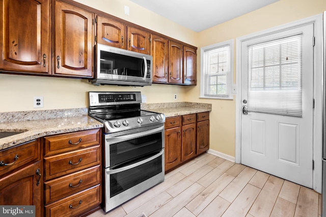 kitchen featuring appliances with stainless steel finishes, light stone counters, and light hardwood / wood-style floors