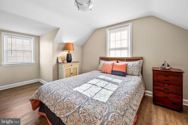 bedroom with dark wood-type flooring, multiple windows, and vaulted ceiling