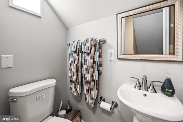 bathroom featuring sink, toilet, and vaulted ceiling