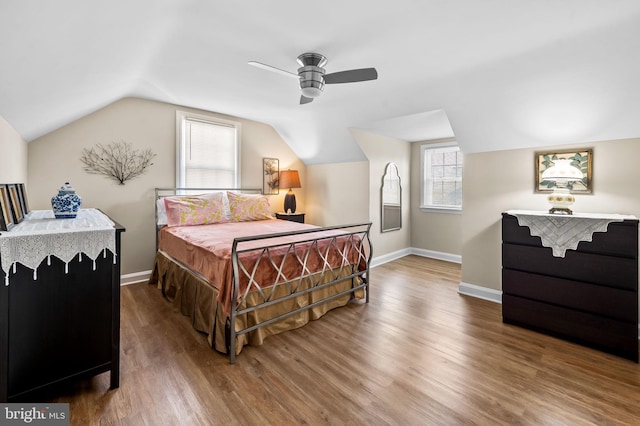 bedroom featuring multiple windows, hardwood / wood-style floors, vaulted ceiling, and ceiling fan