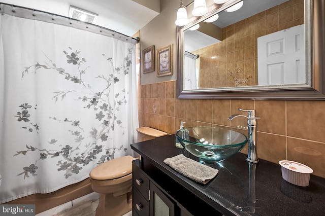 bathroom featuring toilet, vanity, and tile walls