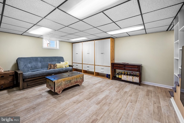 living room with light wood-type flooring and a paneled ceiling