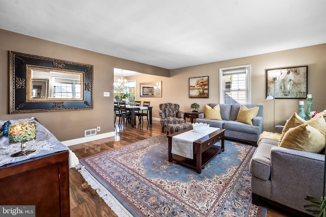 living room with dark wood-type flooring and an inviting chandelier