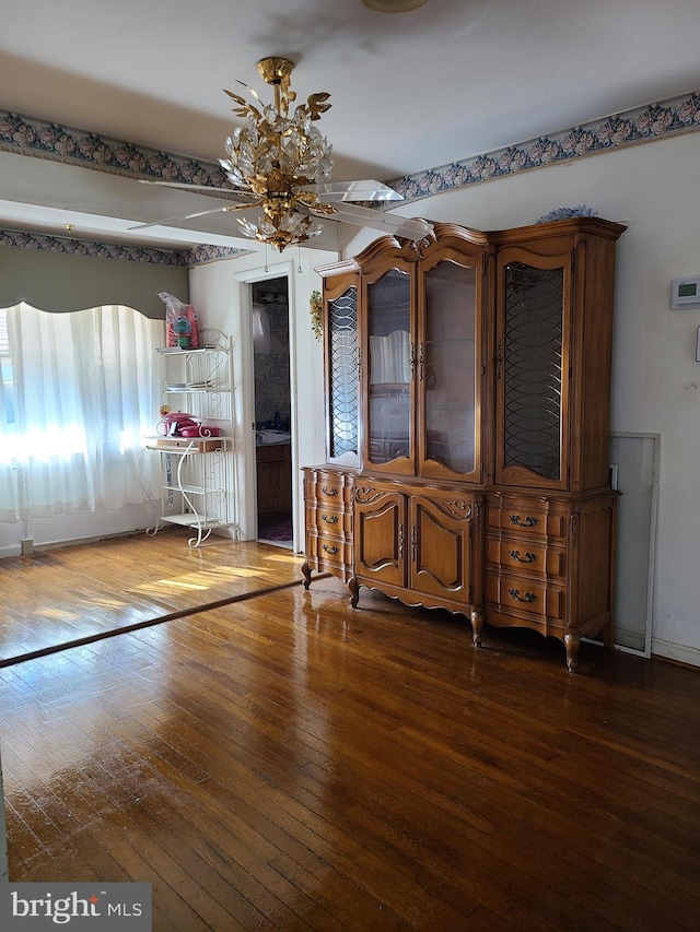 unfurnished dining area with dark wood-type flooring and an inviting chandelier