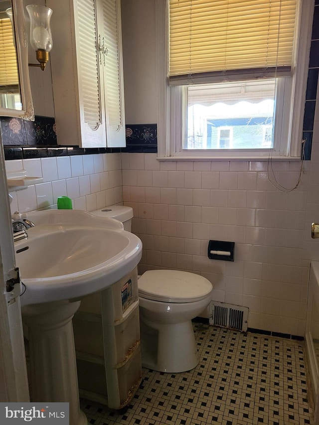 bathroom with tile patterned flooring, tile walls, and toilet