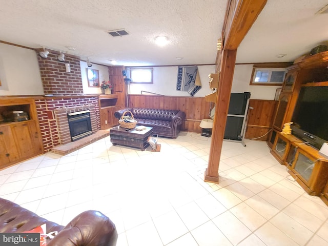 living room with a brick fireplace, wooden walls, and a textured ceiling