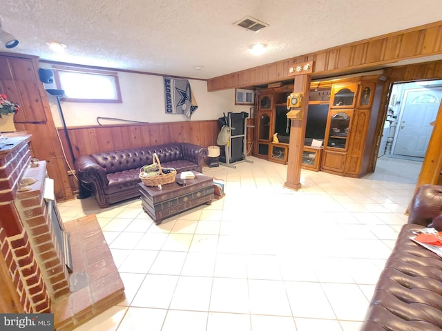 living room with light tile patterned floors, a textured ceiling, and wood walls