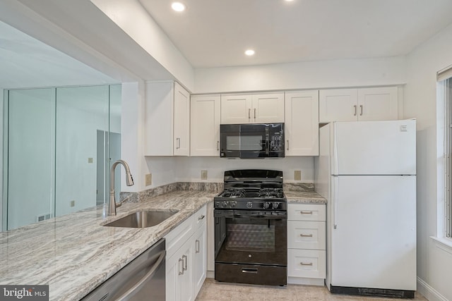 kitchen featuring white cabinetry, light stone counters, black appliances, and sink