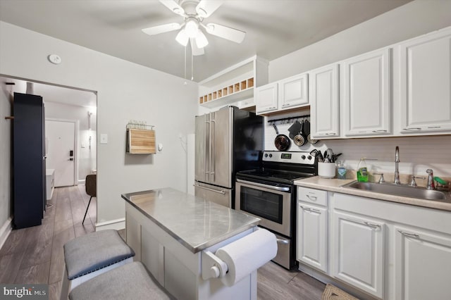 kitchen with stainless steel appliances, sink, white cabinetry, light hardwood / wood-style floors, and ceiling fan