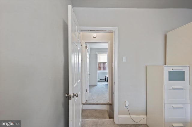 hall featuring light carpet and baseboard heating