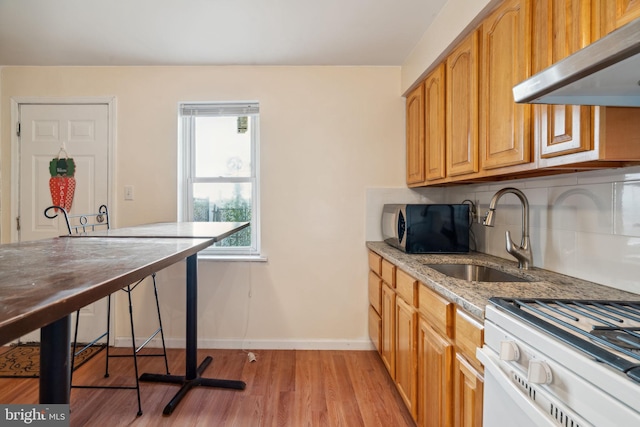 kitchen featuring range hood, light stone counters, white range oven, light hardwood / wood-style floors, and sink