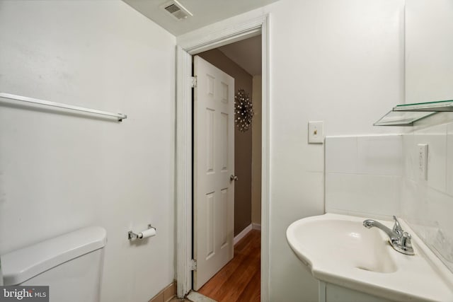 bathroom featuring toilet, sink, and wood-type flooring