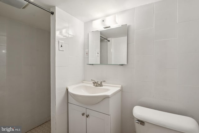 bathroom with tile walls, vanity, a shower, and toilet