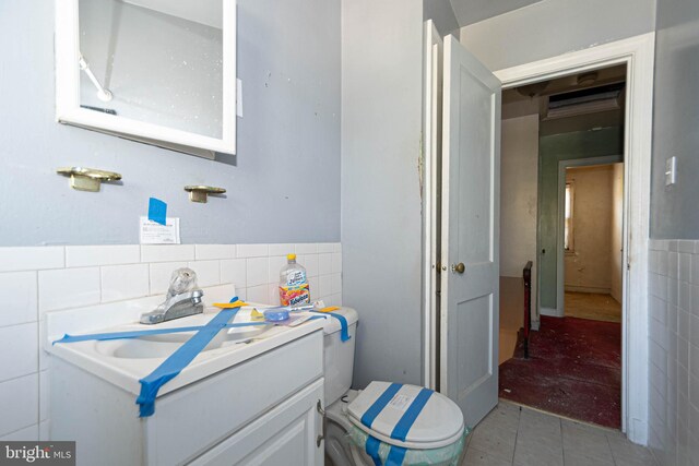 bathroom with tile walls, vanity, toilet, and tile patterned floors