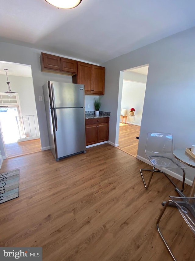 kitchen featuring hardwood / wood-style floors, hanging light fixtures, and stainless steel refrigerator