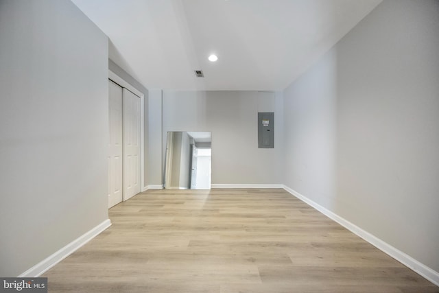 corridor with light hardwood / wood-style flooring and electric panel