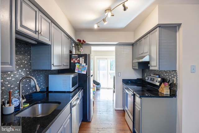 kitchen with appliances with stainless steel finishes, gray cabinetry, sink, and dark hardwood / wood-style flooring