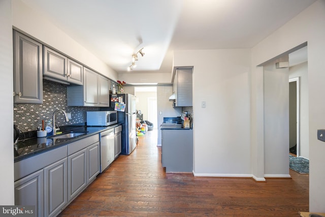 kitchen featuring sink, backsplash, dark hardwood / wood-style flooring, stainless steel appliances, and gray cabinets