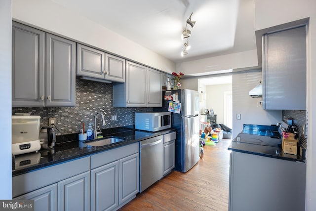 kitchen with sink, backsplash, stainless steel appliances, exhaust hood, and dark hardwood / wood-style floors