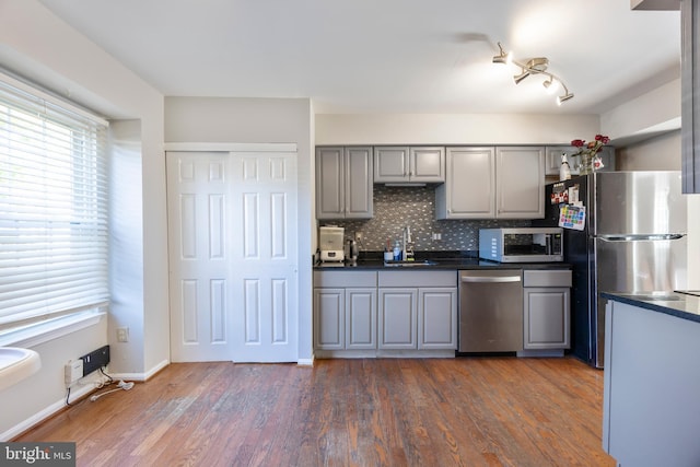 kitchen featuring dark wood-type flooring, backsplash, appliances with stainless steel finishes, and gray cabinets