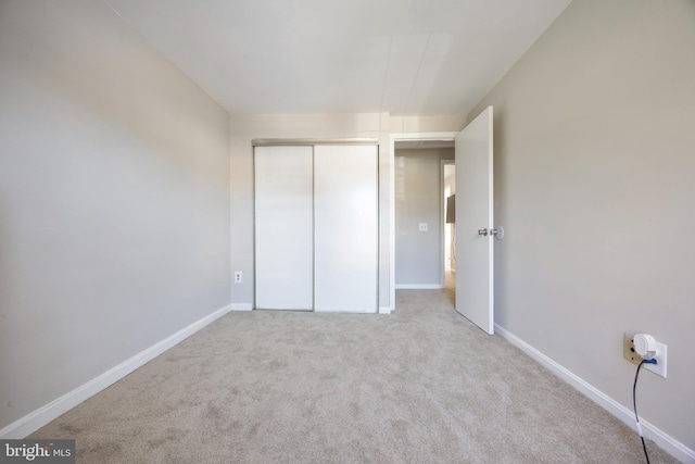 unfurnished bedroom with a closet and light colored carpet