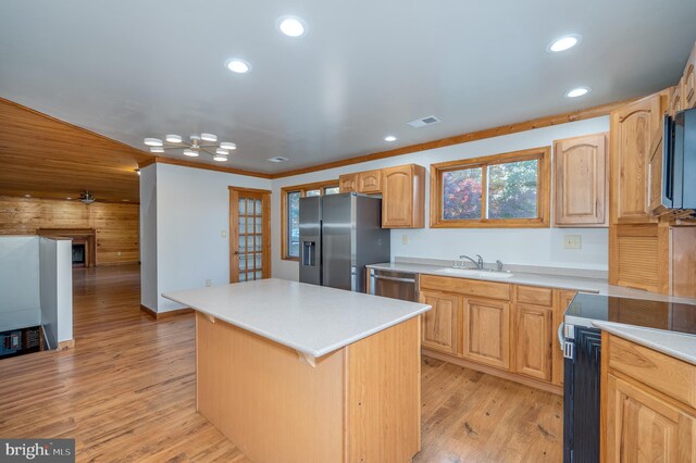 kitchen with a center island, light wood-type flooring, stainless steel appliances, and ornamental molding