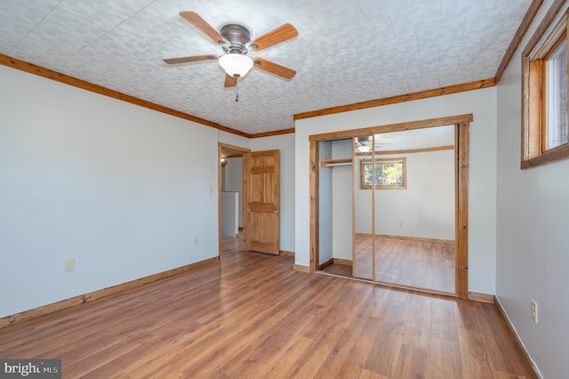 unfurnished bedroom featuring a closet, hardwood / wood-style floors, ceiling fan, and crown molding