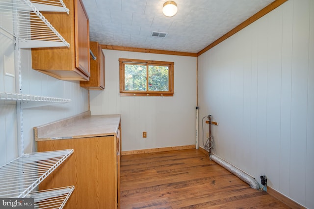 laundry area with cabinets, hardwood / wood-style floors, ornamental molding, and wooden walls