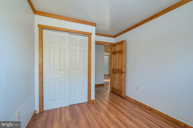 unfurnished bedroom with crown molding, light hardwood / wood-style flooring, and a closet