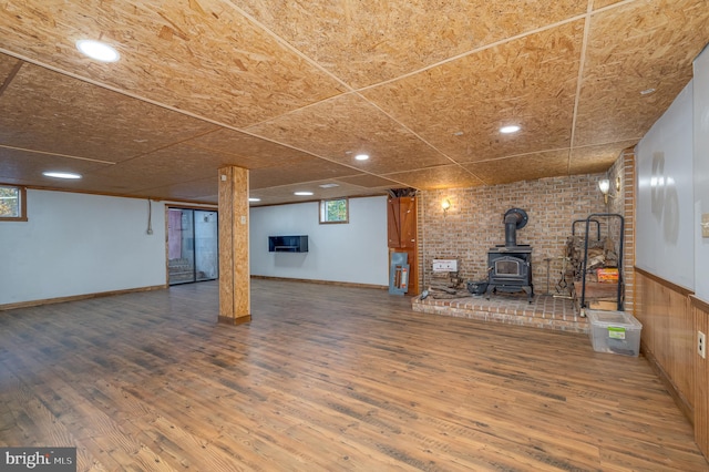 basement featuring a wood stove and wood-type flooring