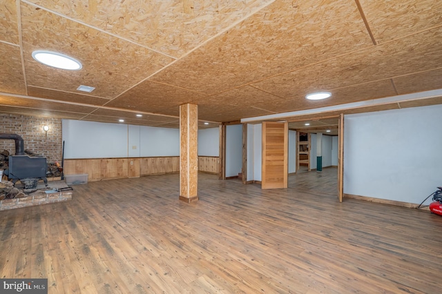 basement with wood-type flooring and a wood stove